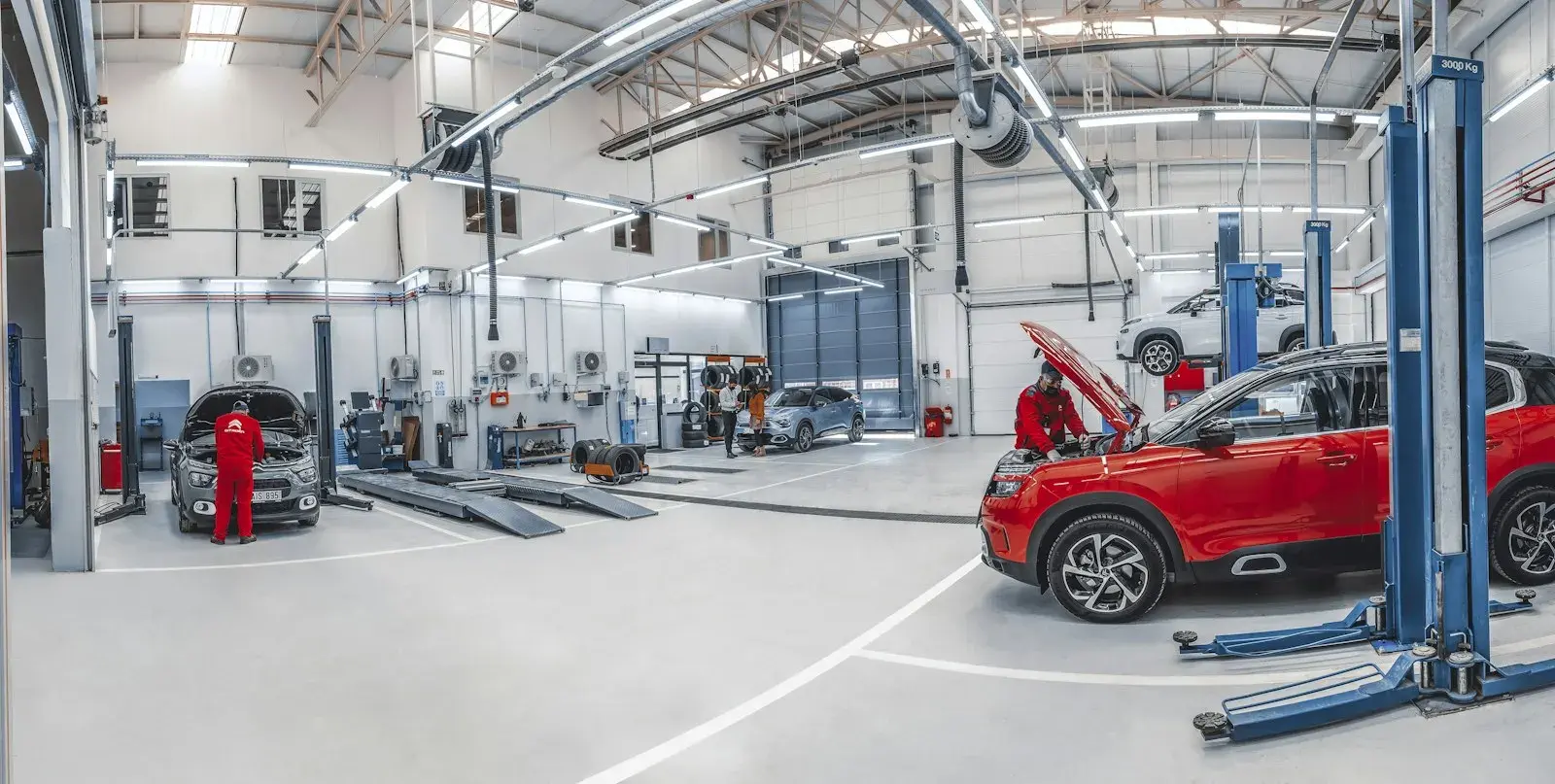 Mechanics working on cars in a bright, spacious automotive repair workshop