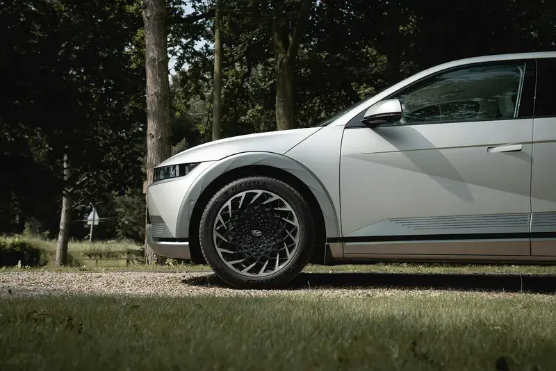 A modern silver car parked on a gravel road
