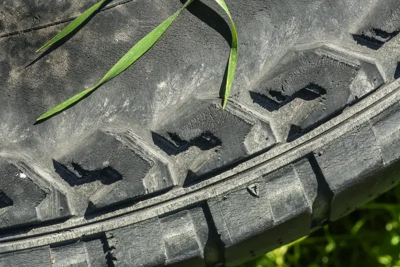 Close-up of a worn tire tread with grass blades